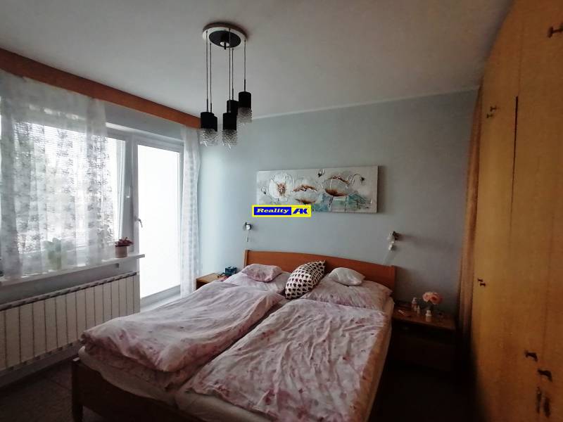 Hálószoba családi házban franciaággyal, szekrénnyel és erkélyajtókkal.