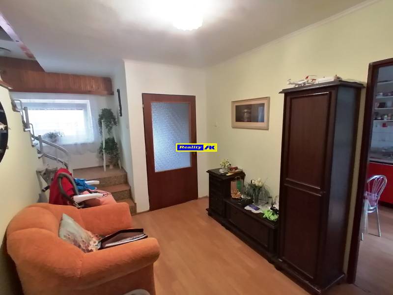 Nappali egy családi házban fa bútorokkal és lépcsővel.