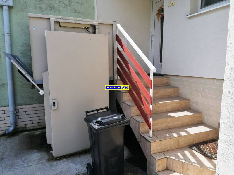 A J.Š.Šikuru utcai családi ház bejárata előtt lépcső és lift található.