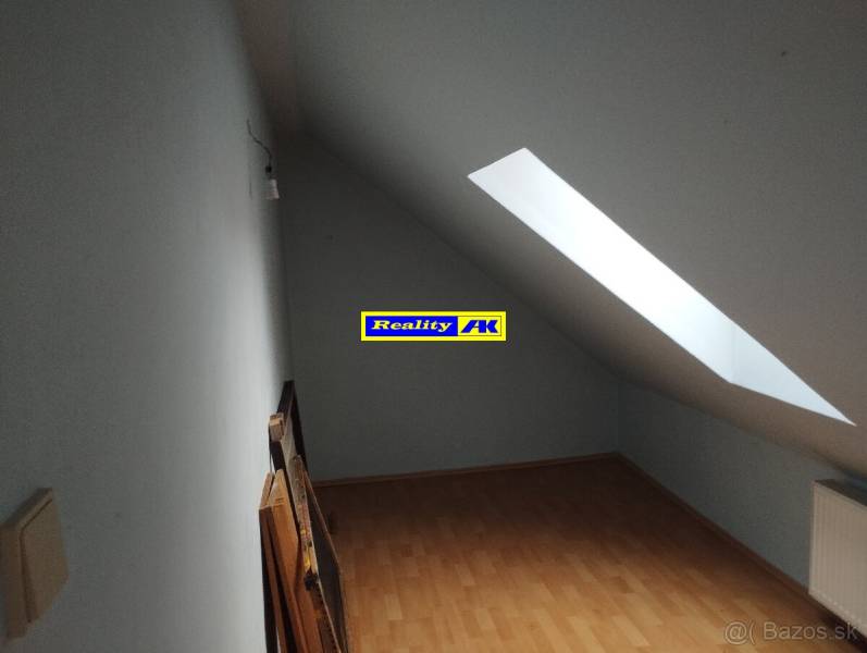 Tetőtéri szoba fa padlóval és tetőablakkal egy családi házban.