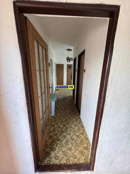 Folyosó egy családi házban szőnyeggel és faajtókkal.