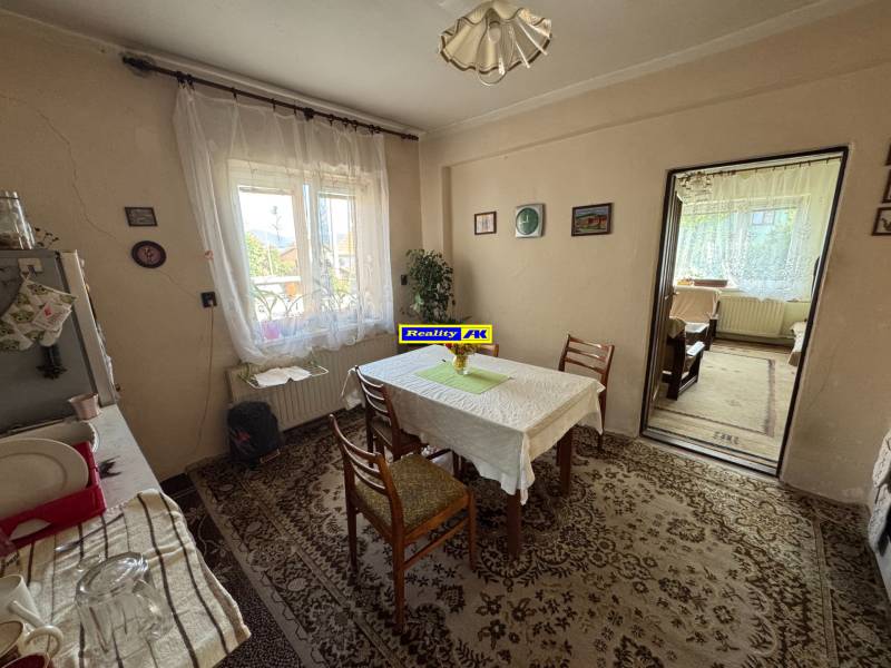 Ebédlő egy családi házban, asztallal, székekkel, szőnyeggel és ablakkal, kilátással.