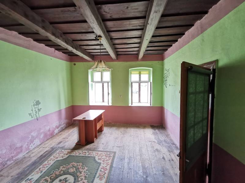 Szoba egy családi házban, fa mennyezettel, régi asztallal és szőnyeggel.