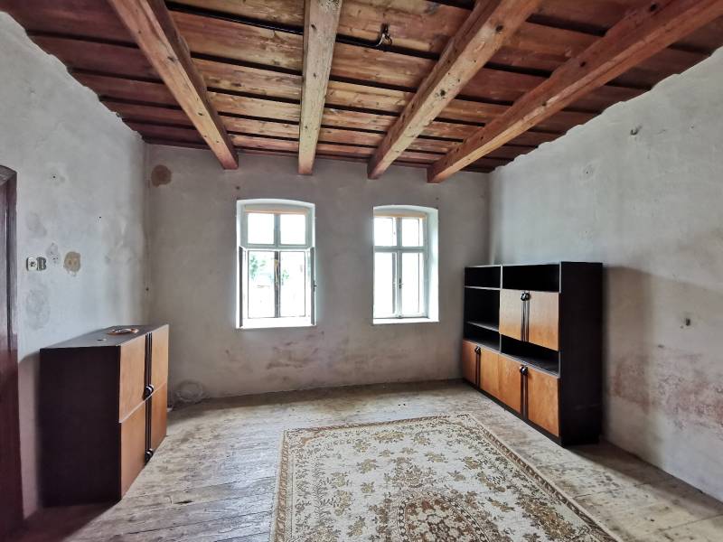 Szoba családi házban fa mennyezettel, ablakok, szekrények, szőnyeg a padlón.