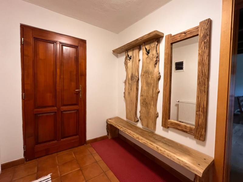 Fa pad és fogas természetes tükörrel egy családi ház belső terében.