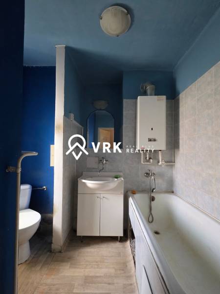 Fürdőszoba egy kétszobás lakásban káddal, mosdóval és WC-vel, a falak színárnyalatai kékek.