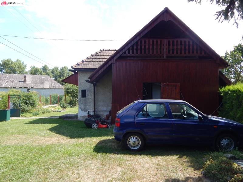Autó parkol a Klížska Nemá-i ház mellett, zöld gyep és fák veszik körül.