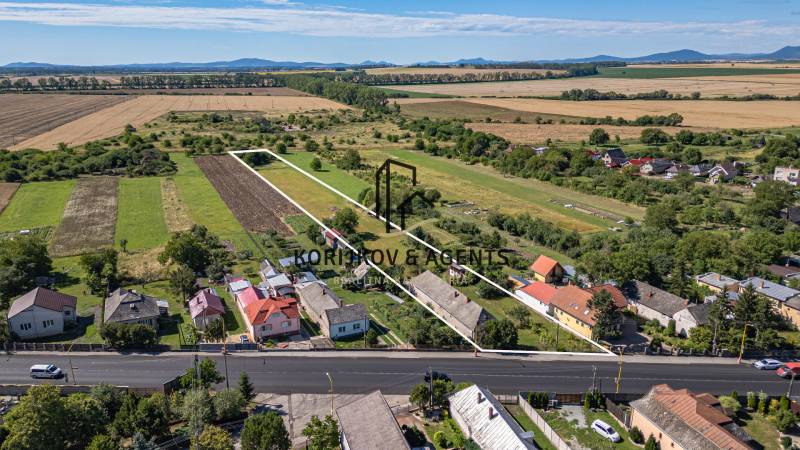Lakóövezetek Sečovce-ben, zöld mezők, néhány ház és egy nagy út elöl.