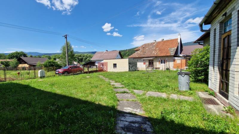 Családi ház Mníšek nad Hnilcom-ban gyepes udvarral, terasszal és parkolóval a tiszta ég alatt.