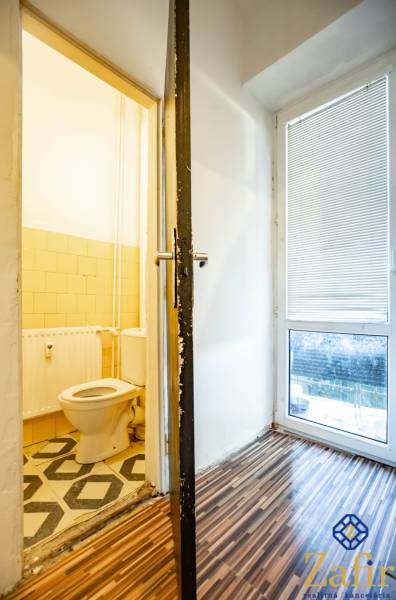 Fürdőszoba egy háromszobás lakásban fa padlóval és WC-vel.