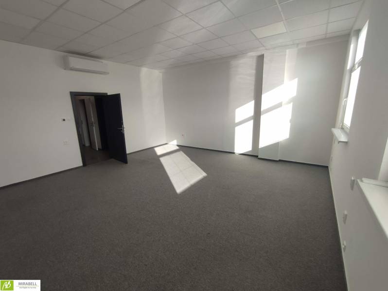 Irodák fehér falakkal, szőnyeggel és légkondicionálással, egyszerű munkaterület a munkavégzéshez.