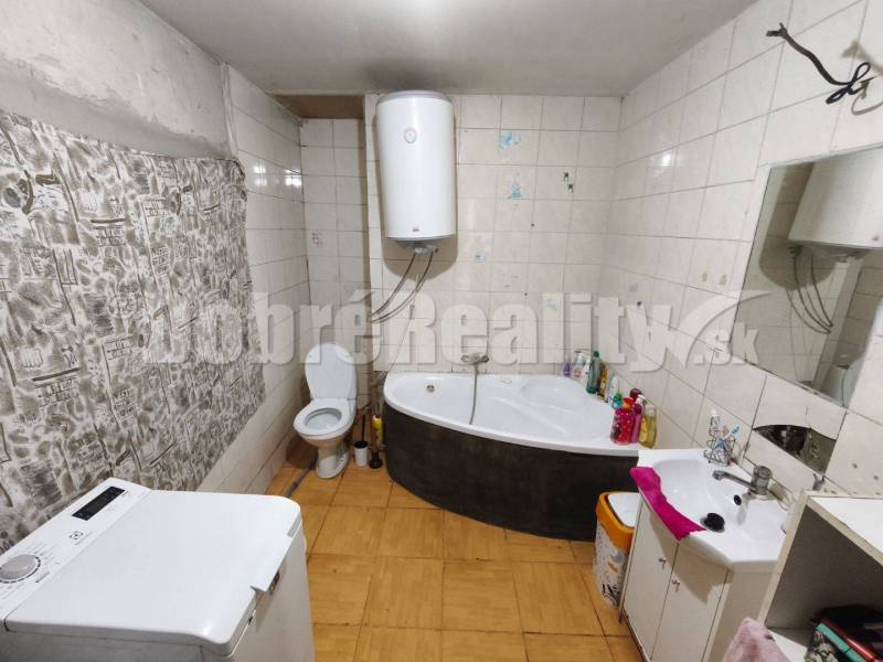 Fürdőszoba káddal, mosógéppel, WC-vel és bojlerrel a családi házban.