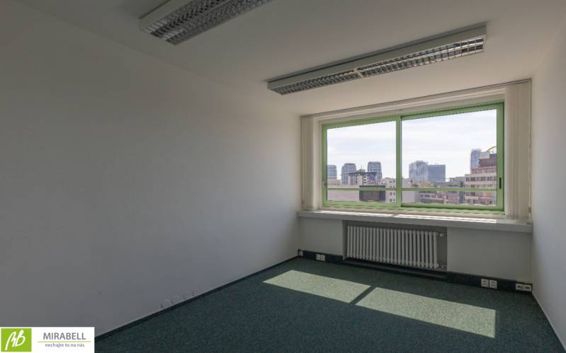 Üres iroda kilátással a város panorámájára egy nagy ablakon keresztül.