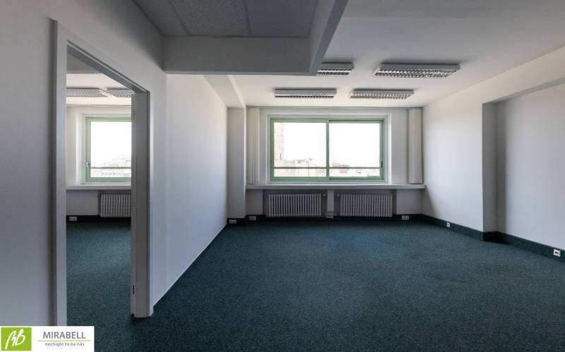 Tágas irodák nagy ablakkal és szőnyeggel, bőséges természetes fénnyel.