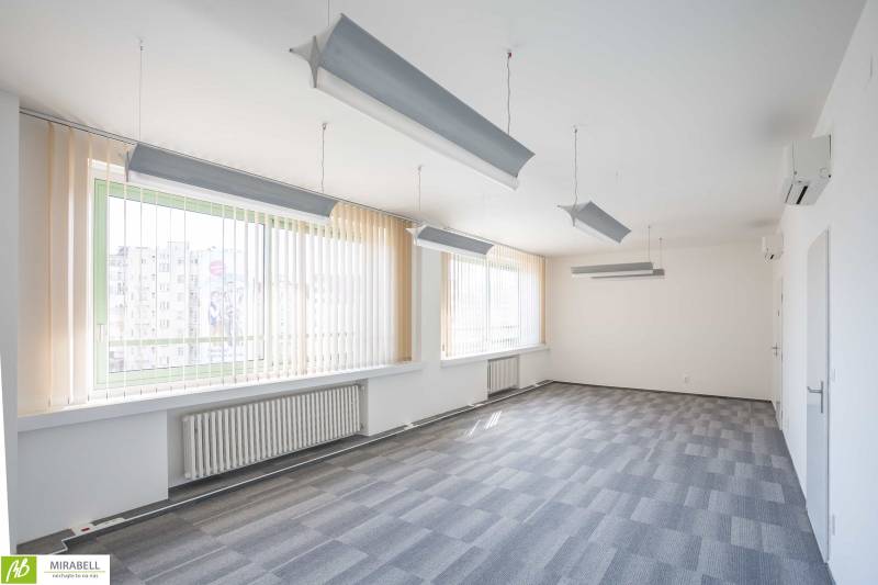 Tágas irodák függőlámpákkal és függőleges redőnyökkel.