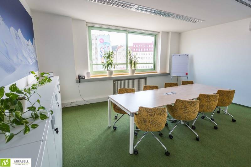 Irodák asztallal és székekkel, növényekkel és ablakkal, kilátással a városra.