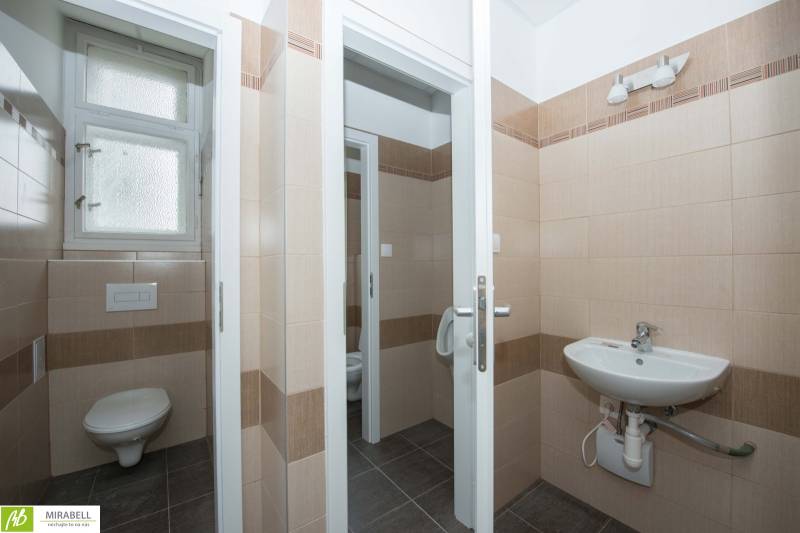 Irodai fürdőszoba bézs csempékkel és mosdóval.