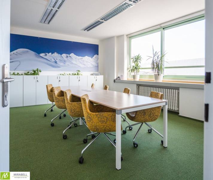 Irodák zöld szőnyeggel, sárga székekkel és nagy hegyi fotótapétával.