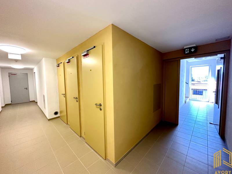 Folyosó több ajtóval egy kétszobás lakásban, világos csempe és vészkijárat.