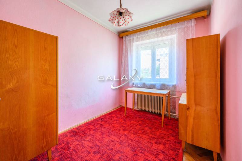Egy szoba családi házban rózsaszín falakkal, bútorokkal és piros szőnyeggel.