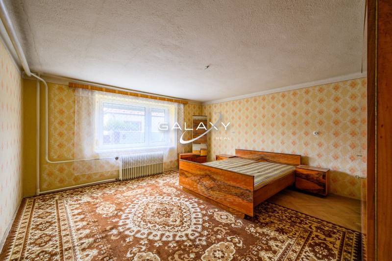 Hálószoba ággyal, mintás tapétákkal és szőnyegekkel egy családi házban.