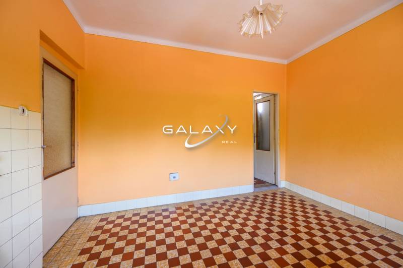 Egy családi ház szobája narancssárga falakkal és csempemintás padlóval.