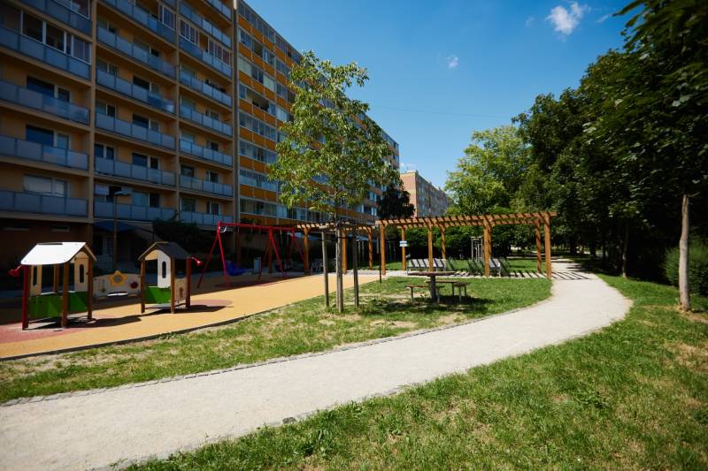 Játszótér egy lakóházzal Kassán - Juh városrészben, zöldövezettel és járdával körülvéve.