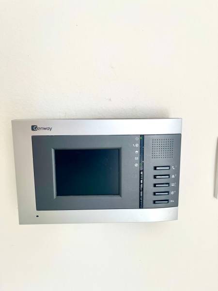 Belső vezérlőpanel egy kétszobás lakásban érintőképernyővel és vezérlőgombokkal.