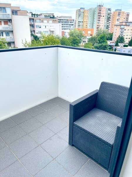 A 2 szobás lakás erkélye rattan székkel és kilátással a környező lakóházakra.