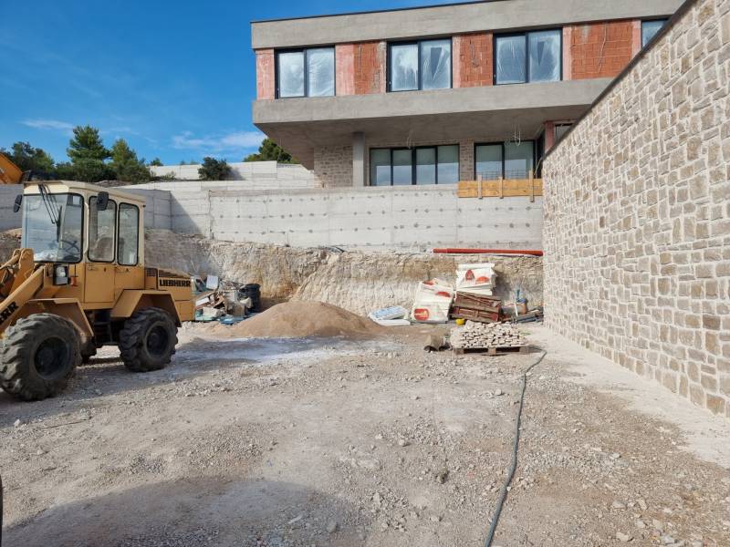 Építkezési terület egy félkész villával Vodice városában, látható egy építőgép és anyag.