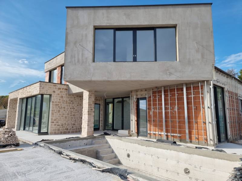 Befejezetlen villa Vodice városában, kő- és téglafalakkal, nagy ablakokkal és terasszal.