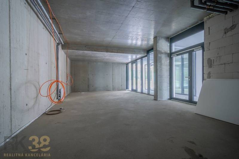 Üzlethelyiség belső tér üvegfallal, betonmennyezettel és elektromos berendezéssel.