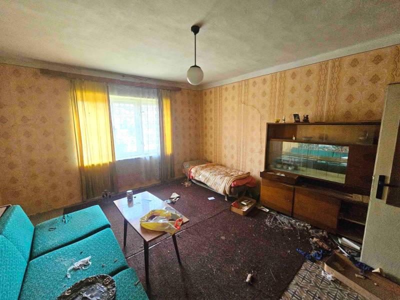 Nappali egy családi házban kanapéval, tapétás fallal és bútorokkal.