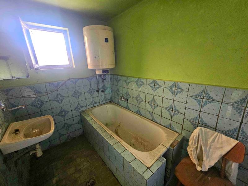 Fürdőszoba káddal és mosdóval egy családi házban, kék csempékkel.