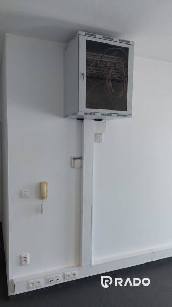 Irodák kommunikációs eszközzel és hálózati elosztóval a fehér falon.