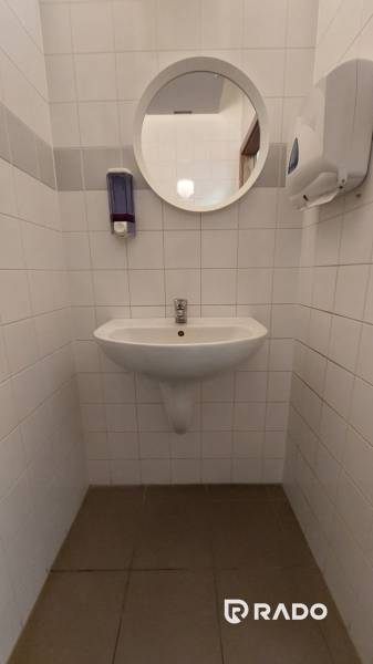 Fehér csempék és mosdókagyló kerek tükörrel az irodában.