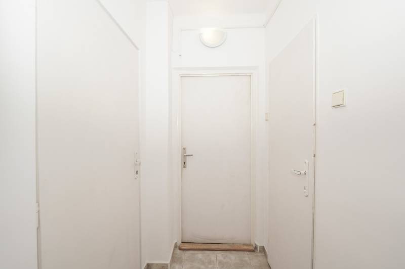 Fehér folyosó zárt ajtókkal az irodában, egyszerű tér járólappal.