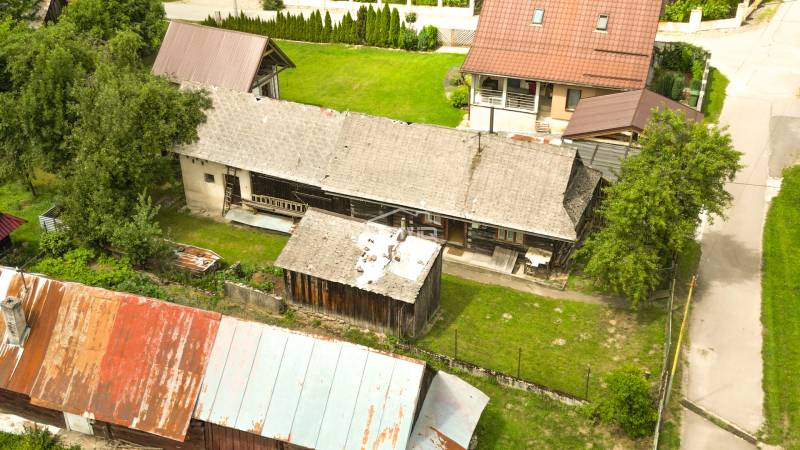 Rusztikus ház Papradnóban, amelyet zöldövezet és melléképületek vesznek körül.