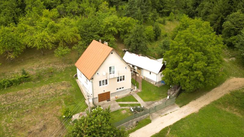Családi ház Papradnóban, füves telekkel és fákkal körülvéve, megközelítési úttal.