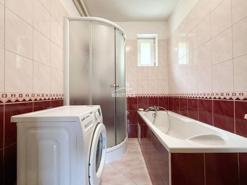 Fürdőszoba káddal, zuhanyzóval és mosógéppel egy családi házban.