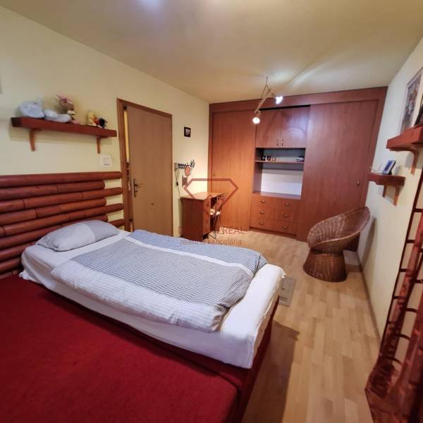 Családi ház hálószobája ággyal, szekrénnyel és rattan székkel.