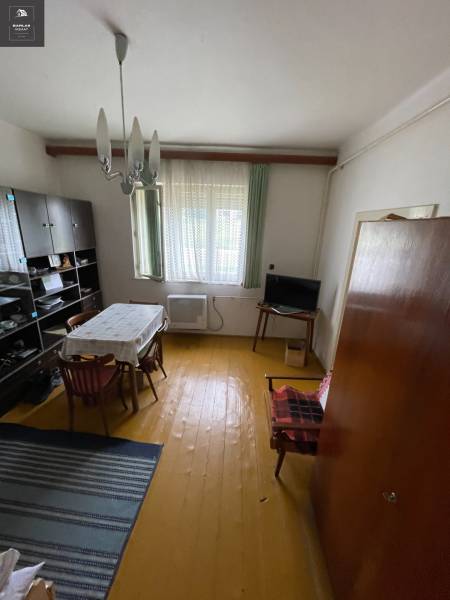 Ebédlő egy családi házban, fa padlóval, egyszerű asztallal és szekrénnyel a falon.