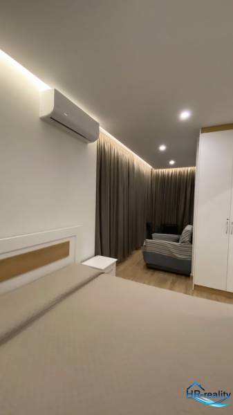 Nyaraló apartman belső tere ággyal, kanapéval, függönyökkel és légkondicionálóval.