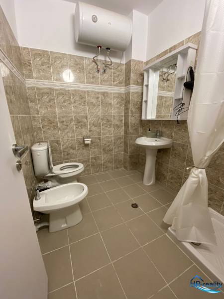 Fürdőszoba egy üdülő apartmanban; mosdó, tükör, WC, bidé és vízmelegítő.
