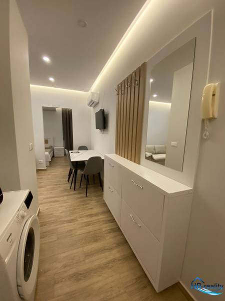 A rekreációs apartman folyosója mosógéppel, tükörrel és étkezőasztallal.