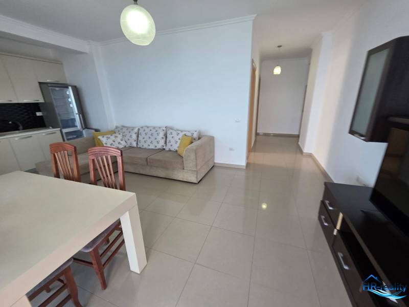 Világos nappali konyhasarokkal, kanapéval és étkezőasztallal a nyaraló apartmanban.