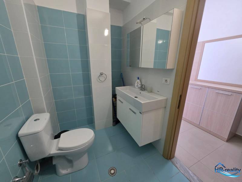 Fürdőszoba világoskék csempékkel a nyaraló apartmanban, mosdó és tükrös szekrény.