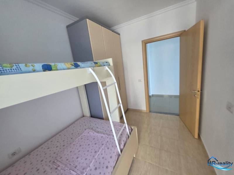 Gyerekszoba emeletes ággyal egy üdülő apartmanban világos falakkal és padlóval.