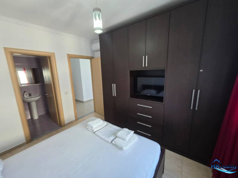 Hálószoba egy üdülő apartmanban nagy gardróbszekrénnyel és csatlakoztatott fürdőszobával.