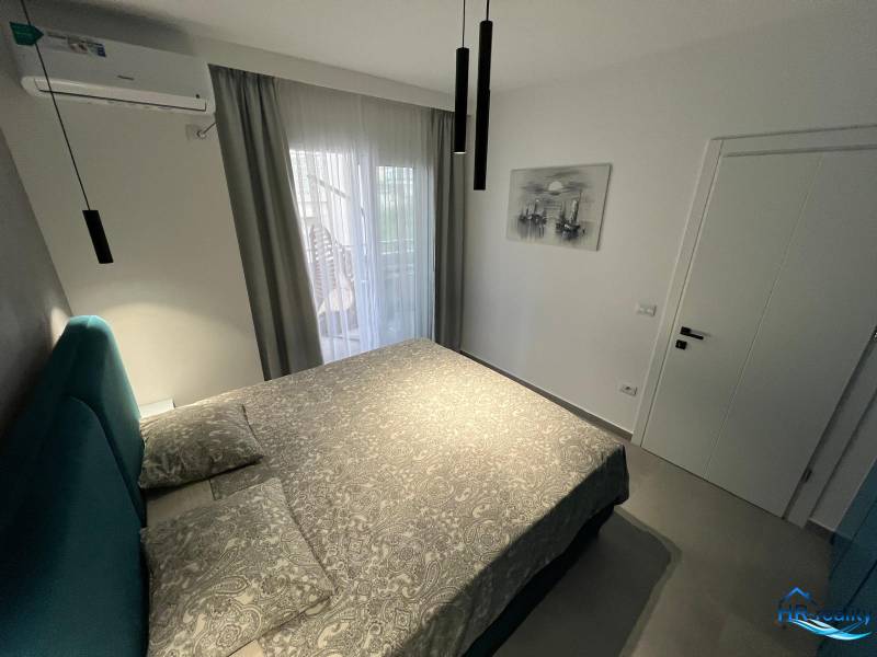 Rekreációs apartman kényelmes ággyal, légkondicionálóval és erkélyajtókkal, kilátással.